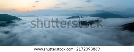 Panorama of sea of clouds around mountain peaks at sunrise