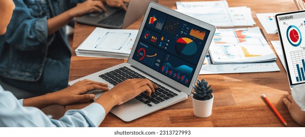 Panorama shot analyst team utilizing BI Fintech to analyze financial report with laptop. Businesspeople analyzing BI power dashboard displayed on laptop screen for business insight. Scrutinize - Powered by Shutterstock