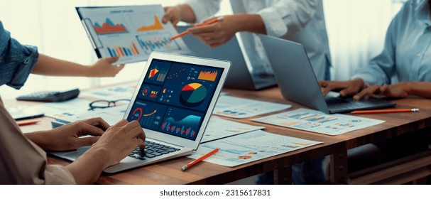 Panorama shot analyst team utilizing BI Fintech to analyze financial report with laptop. Businesspeople analyzing BI power dashboard displayed on laptop screen for business insight. Scrutinize - Shutterstock ID 2315617831