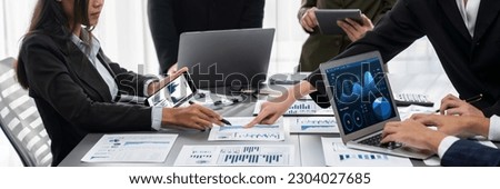 Panorama shot analyst team utilizing BI Fintech to analyze financial report with laptop. Businesspeople analyzing BI data dashboard displayed on laptop screen for business insight. Prodigy