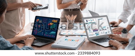 Panorama shot analyst team utilizing BI Fintech to analyze financial report with laptop. Businesspeople analyzing BI power dashboard displayed on laptop screen for business insight. Scrutinize