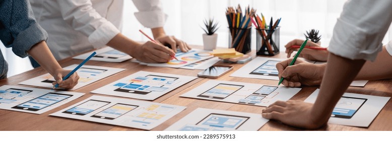 Panorama shot of front-end developer team brainstorming UI and UX designs for mobile app on paper wireframe interface. User interface development team planning for user-friendly UI design. Scrutinize - Shutterstock ID 2289575913