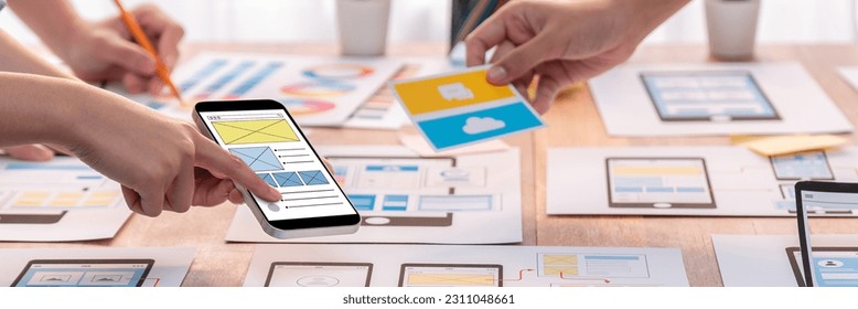 Panorama shot of front-end developer team brainstorming UI and UX designs for mobile app on paper wireframe interface. User interface development team planning for user-friendly UI design. Scrutinize - Shutterstock ID 2311048661