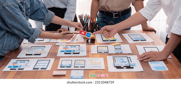 Panorama shot of front-end developer team brainstorming UI and UX designs for mobile app on paper wireframe interface. User interface development team planning for user-friendly UI design. Scrutinize - Shutterstock ID 2311048739