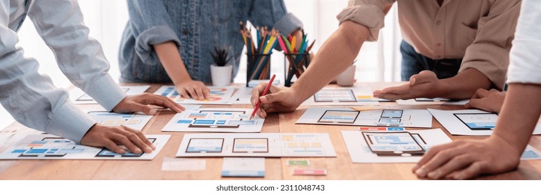 Panorama shot of front-end developer team brainstorming UI and UX designs for mobile app on paper wireframe interface. User interface development team planning for user-friendly UI design. Scrutinize - Shutterstock ID 2311048743