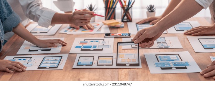 Panorama shot of front-end developer team brainstorming UI and UX designs for mobile app on paper wireframe interface. User interface development team planning for user-friendly UI design. Scrutinize - Shutterstock ID 2311048747