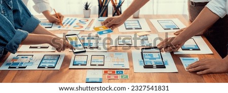 Panorama shot of front-end developer team brainstorming UI and UX designs for mobile app on paper wireframe interface. User interface development team planning for user-friendly UI design. Scrutinize