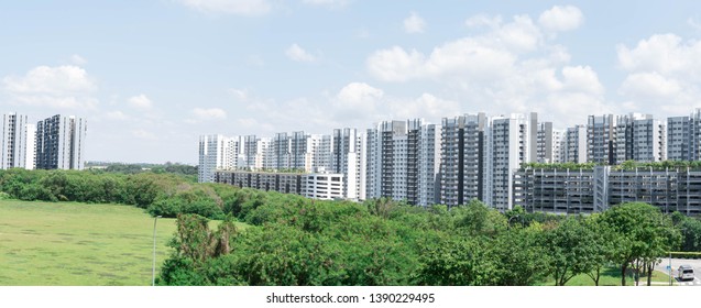 Panorama Shot Of Residential HDB Condominiums In Singapore. Green Forest Park And Blue Sky With Clouds