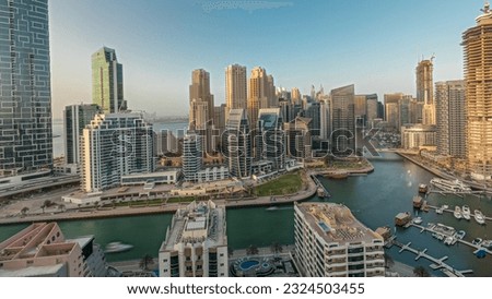 Panorama showing Dubai Marina skyscrapers and JBR district with luxury buildings and resorts aerial. Waterfront with palms and boats floating in canal