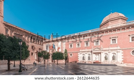 Panorama showing Patriarch's College Square in Valencia timelapse, featuring the historic Museo del Patriarca, fountain with sculptures and Church of the Patriarch. Clear blue sky, Spain.