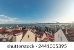 Panorama showing red roofs timelapse and 25 de Abril Bridge, Iconic suspension bridge over Tagus River in Lisbon, Portugal. Aerial view from Miradouro de Santa Catarina. Classic Viewpoint at sunny day