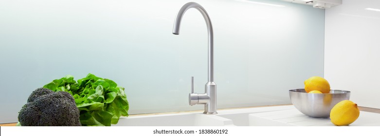 Panorama Of Simple, White Kitchen Sink With Silver Tap And Glass Backsplash