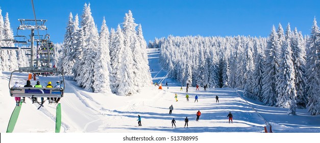 Panorama of ski resort, slope, people on the ski lift, skiers on the piste among white snow pine trees - Shutterstock ID 513788995