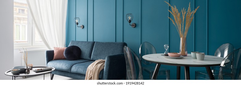 Panorama Of Small And Nice Designed Living Room With Modern Dining Table And Stylish Blue Wall With Molding