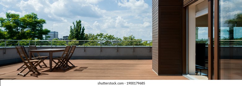 Panorama of spacious terrace with wooden floor and furniture, and amazing view - Shutterstock ID 1900179685