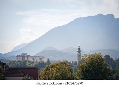 Panorama of the suburbs of Villach with a selective blur on steeple clocktower of Pfarrhoff Sankt Martin Kirche, or the Parish Church of Saint Martin, catholic church of Villach, Austria, Carinthia