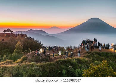 Panorama of Sundoro volcano from Sikunir peak, Dieng Plateau, Indonesia in golden hours with soft misty horizon layer background and foreground of people wait for sunrise on peak.