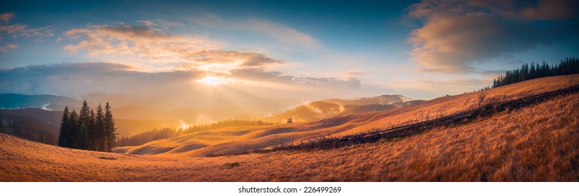 Panorama of sunset in a Carpathian mountain valley with wonderful gold light on a hills
