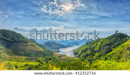 Panorama sunset hillside Ta Dung hydro lake with mountains blue swirled large lake with islands, far away from the real little house idyllic rural countryside scene Vietnam