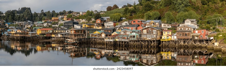 A panorama of the town of Castro on Chiloe, with the colorful, wooden stilt houses reflected in the shallow water.