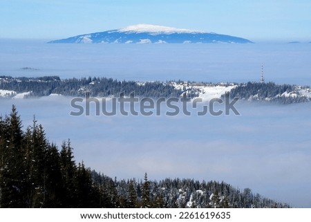 Panorama from trail to Hala Gasienicowa in Tatra Mountains in winter scenery. Babia Gora Peak on horizon. Tatra National Park, Poland. Interesting phenomenon of inversion with clouds.