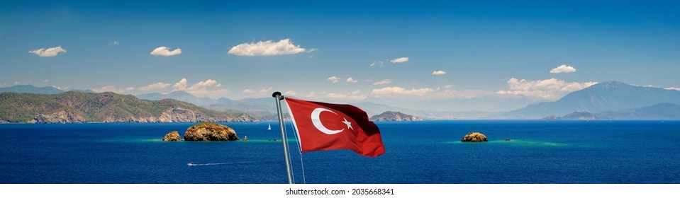 Panorama of Turkish Riviera, coast of Aegean Sea with small rocky islands. Marine landscape with Turkish flag near the Fethiye resort, Turkey.