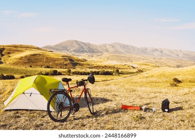 Panorama of unloaded touring red bicycle by green tent. Camping and bicycle touring concept Travel around Armenia by bicycle in mountains in autumn - Powered by Shutterstock