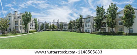 Panorama view apartment building complex with grassy backyard in Palo Alto, California, USA. Summer cloud blue sky