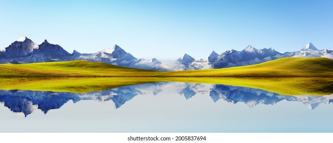 Panorama view of beautiful snow-capped mountain and grassland  landscape with tranquil lake reflection