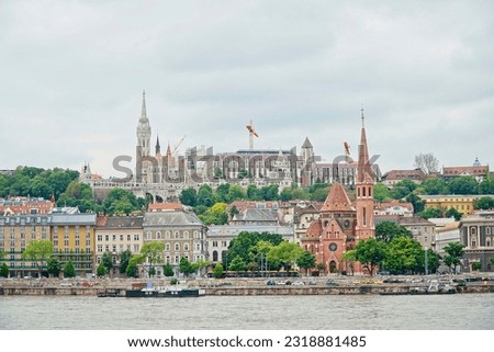 Panorama view of Budapest with Fisherman's Bastion, Matthias Church, Saint Anne Parish and Calvinist Church in Buda, Hungary. Yellow tram running on the Danube bank. Tall Cranes at Buda Castle.