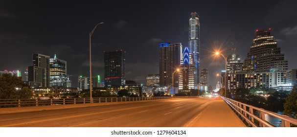 Panorama View Downtown Austin At Night With Traffic Light Trail Lead To Texas State Capitol Building. View From Pedestrian Sidewalk On Bridge Across Colorado River