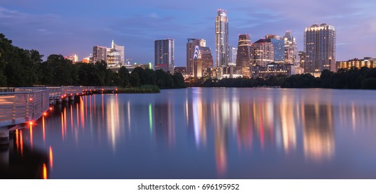 Panorama view of Downtown Austin, Texas, USA skylines reflection on the Colorado River at twilight. View from Ann and Roy Butler Hike-and-Bike Trail and boardwalk at Lady Bird Lake is on the left.