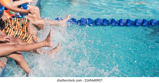 Panorama view group of diverse multiethnic children kicking splashing water at poolside of swimming class in North Texas, America. Kids with swimwear at swimming pool class learning to swim - Powered by Shutterstock