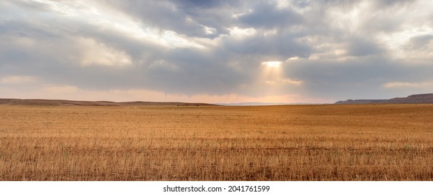 panorama view from harvested Wheat field with partly cloudy sky with sunlight passing through in Kurdistan province, iran