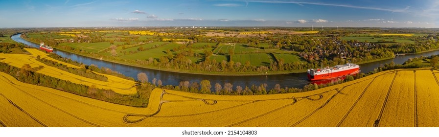 Panorama view of Kiel Canal with container ship and ferry with raps fields along canal. Container cargo ship and ferry on the Kiel Canal between Baltic sea and North Sea Schleswig Holstein, Germany.