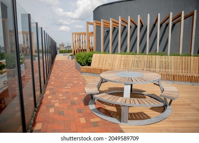 Panorama View Of Modern Rooftop Terrace With Dark Wood Deck Flooring, Plants, Brick Fence And Black Garden Furniture