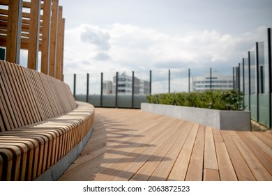 Panorama View Of Modern Rooftop Terrace With Dark Wood Deck Flooring, Plants, Brick Fence And Black Garden Furniture