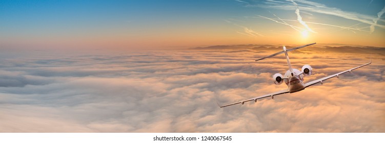 Panorama View Of Private Jet Plane Flying Above Dramatic Clouds During Sunset.