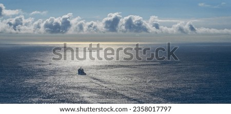 panorama view of a ship heading out to sea with bright morning sun scintillation on the water