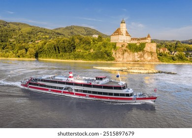 Panorama of Wachau Valley with castle Schonbuhel above the Danube River against tourist boat in Lower Austria, Austria.