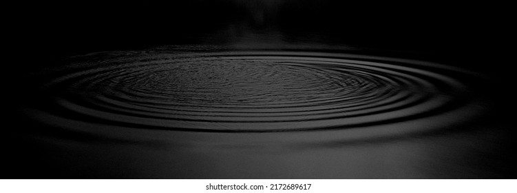 Panorama Water ripples from a drop of water in the dark. water drop dark tone. Abstract black circle water drop ripple. Liquid texture background.Rippled liquid with mood effect in black and white.