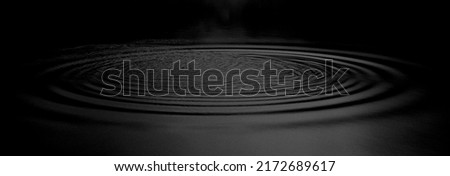 Panorama Water ripples from a drop of water in the dark. water drop dark tone. Abstract black circle water drop ripple. Liquid texture background.Rippled liquid with mood effect in black and white.