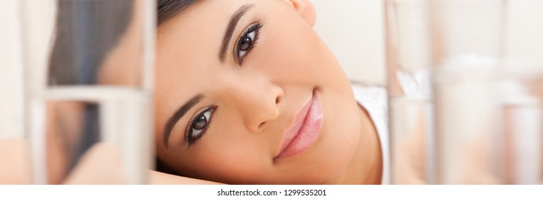 Panorama web banner portrait of a beautiful young Latina Hispanic young woman or girl looking thoughtful resting on her hands looking through glasses of water