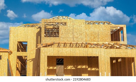 Panorama White Puffy Clouds Unfinished House Structure With Timber Frame And Cork Wall Insulation. Exterior Of An Under Construction Two-storey House Against The Clear Blue Sky Background.