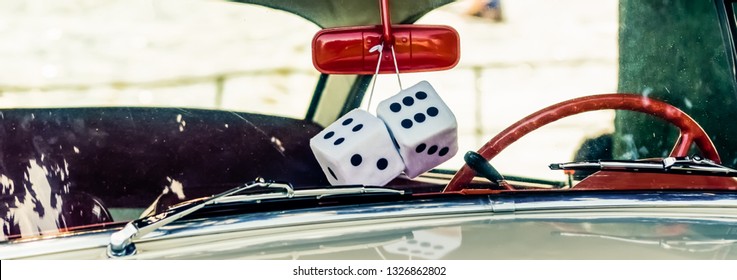 Panorama of white sponge dice hanging from a red mirror in a vintage car