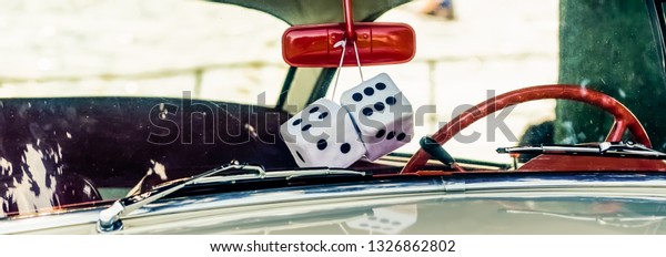 Panorama of white sponge dice hanging from a red\
mirror in a vintage\
car