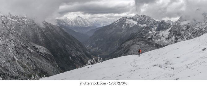 Panorama Of Young Woman Carrying Orange Backpack Stands On Cascade Pass Trail, On The Way To Sahale Glacier Camp, North Cascades National Park, WA, USA. Concept Of Solo Female Traveler.