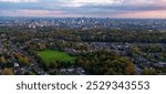 Panoramic Aerial Image of Manchester at sunset, showcasing the city skyline and surrounding residential areas from the vantage point of Heaton Park.