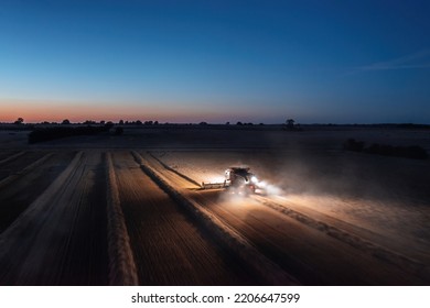 Panoramic aerial landscape view of working combine harvester at night with lights illuminating the field - Shutterstock ID 2206647599