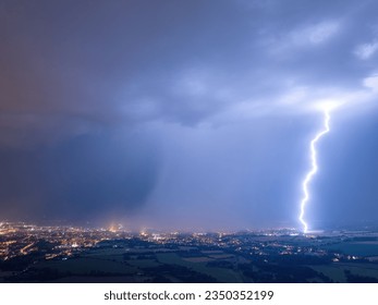 Panoramic aerial shot of a city hit by strong lightning. Dramatic, real drone shot of a massive storm. Lightning between the clouds and the ground.  - Powered by Shutterstock